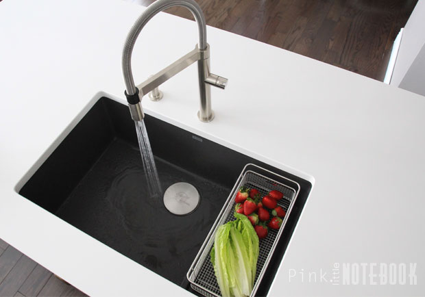 Black BLANCO Silgranit sink with faucet and colander on white countertop