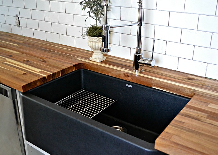 Large black Silgranit style farmhouse sink with butcher block countertop