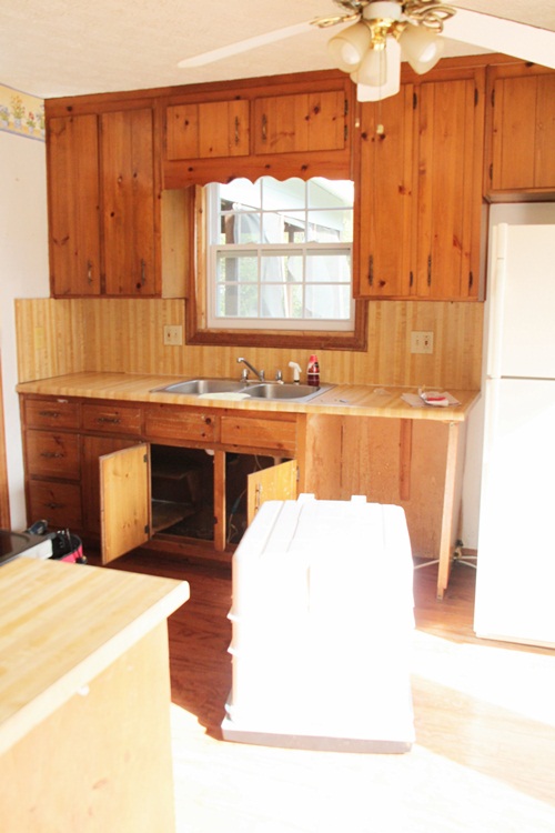 Kitchen before renovation with traditional wood cabinets and small sink
